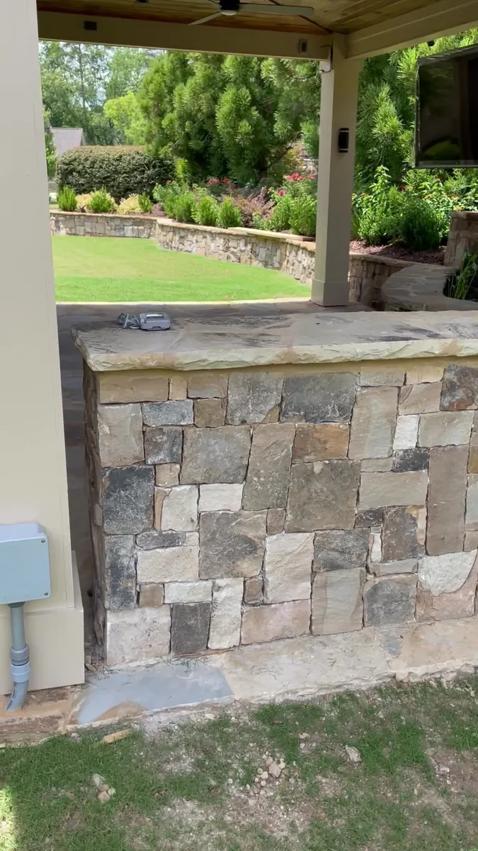 Stone outdoor kitchen under a covered porch
