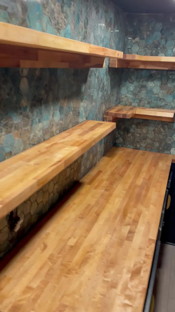 Floating wood shelves on a copper-patina wall