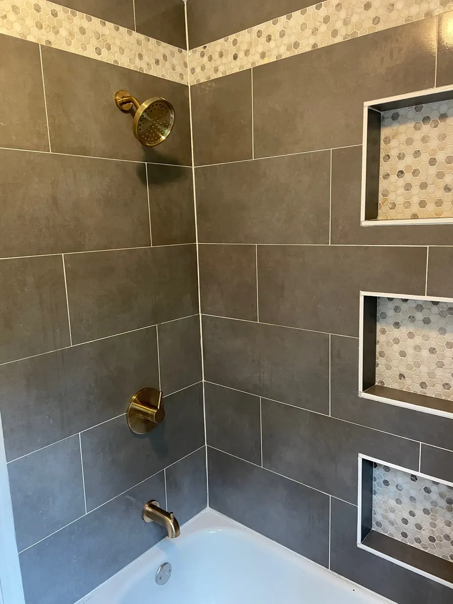 Tiled shower with brass fixtures and inset niches
